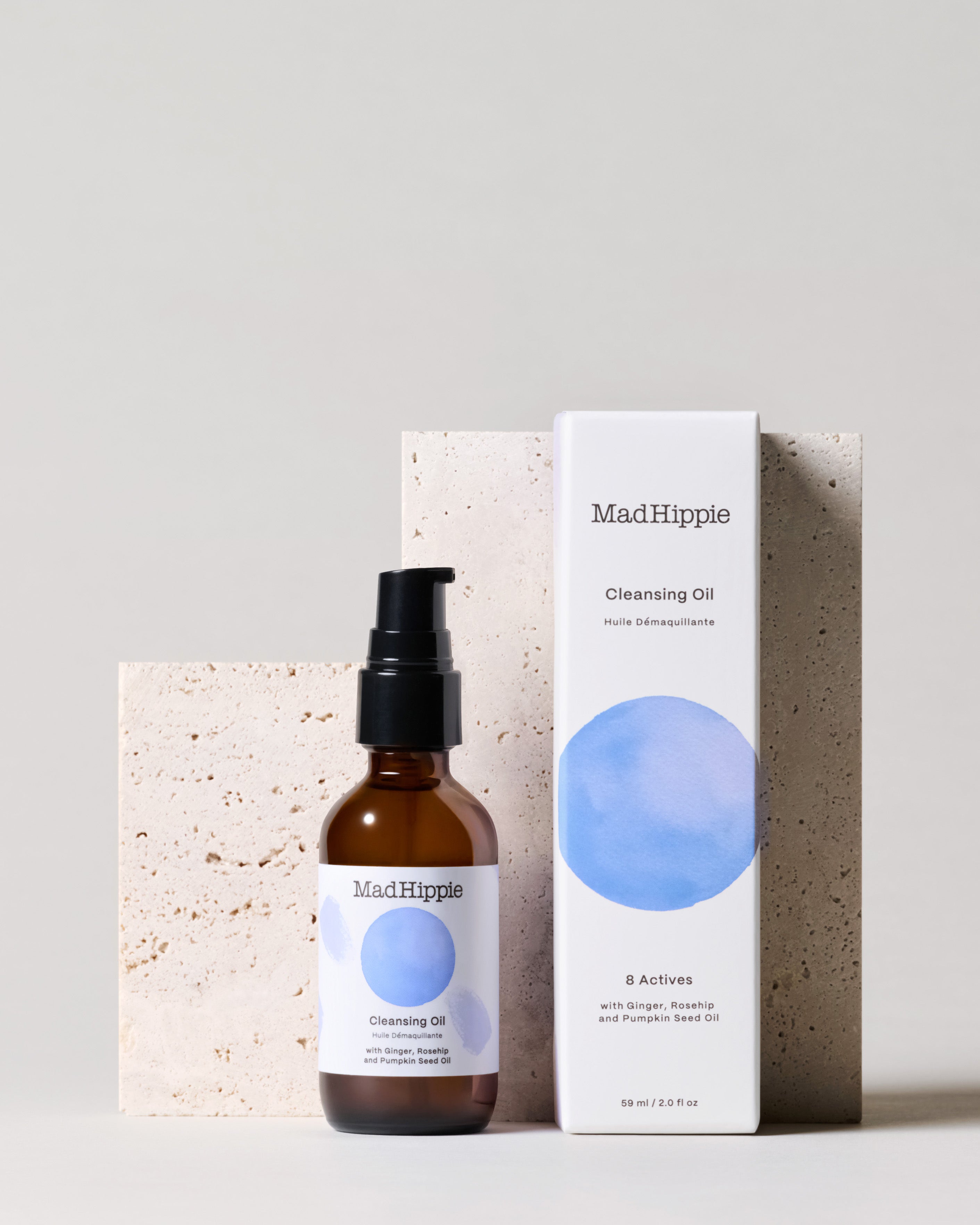 Cleansing Oil bottle + box in front of stone slab, with grey background