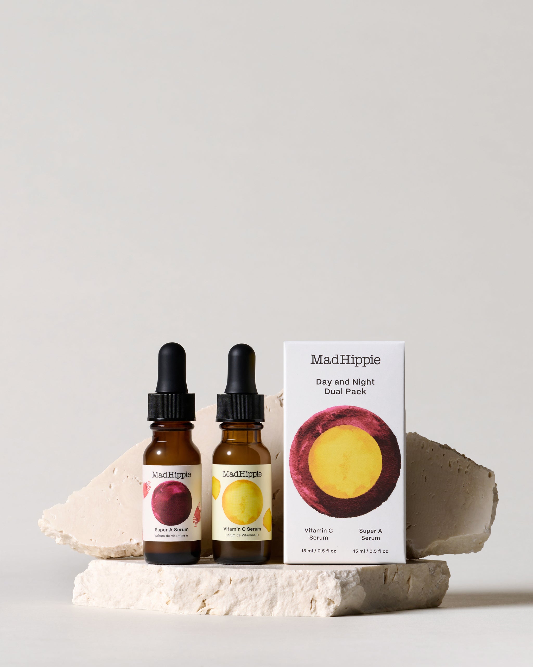 Bottles of Vitamin C Serum + Super A Serum + Dual Pack box, on stone slab with grey background