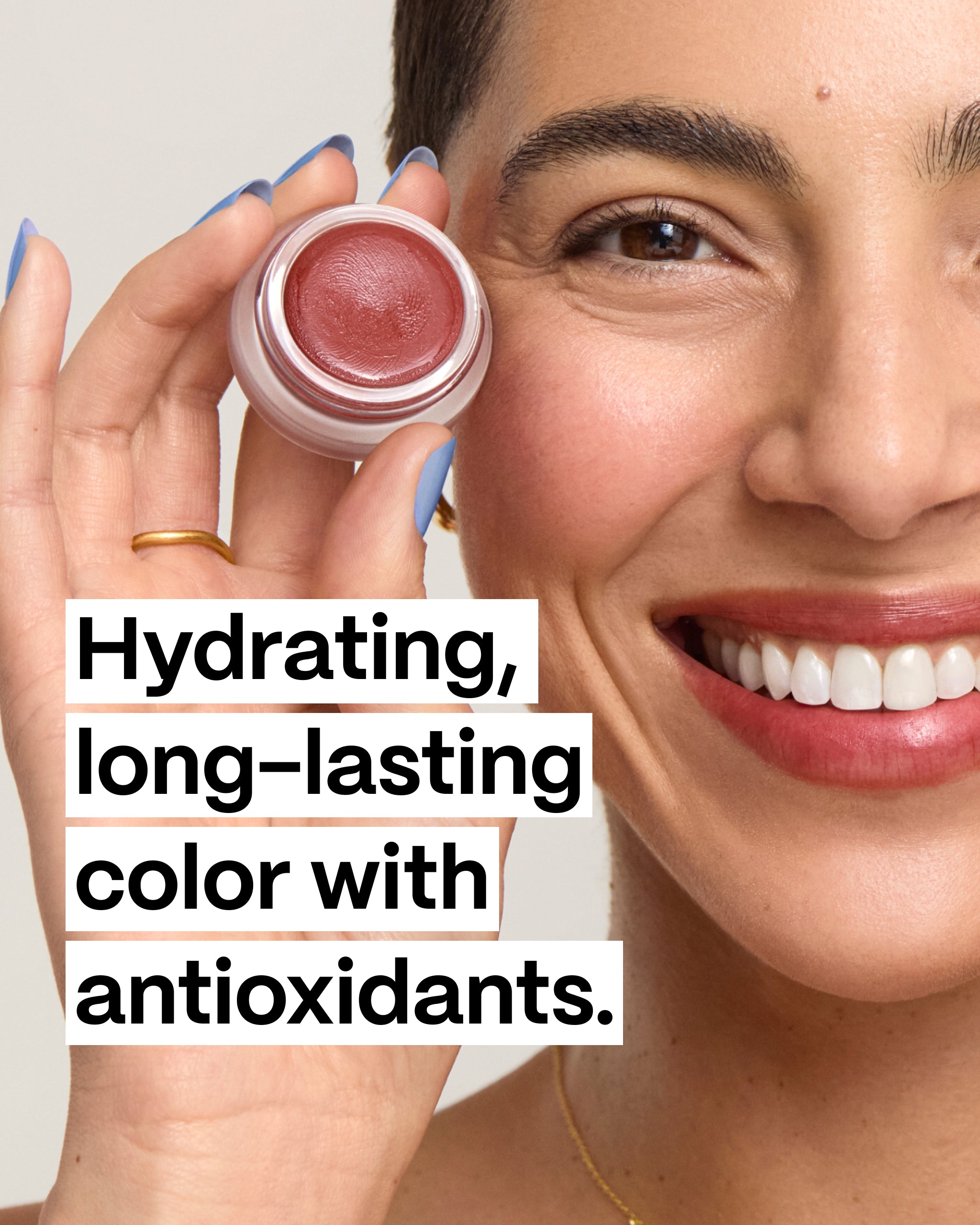 Model smiling & holding and open Fig Cheek & Lip Tint