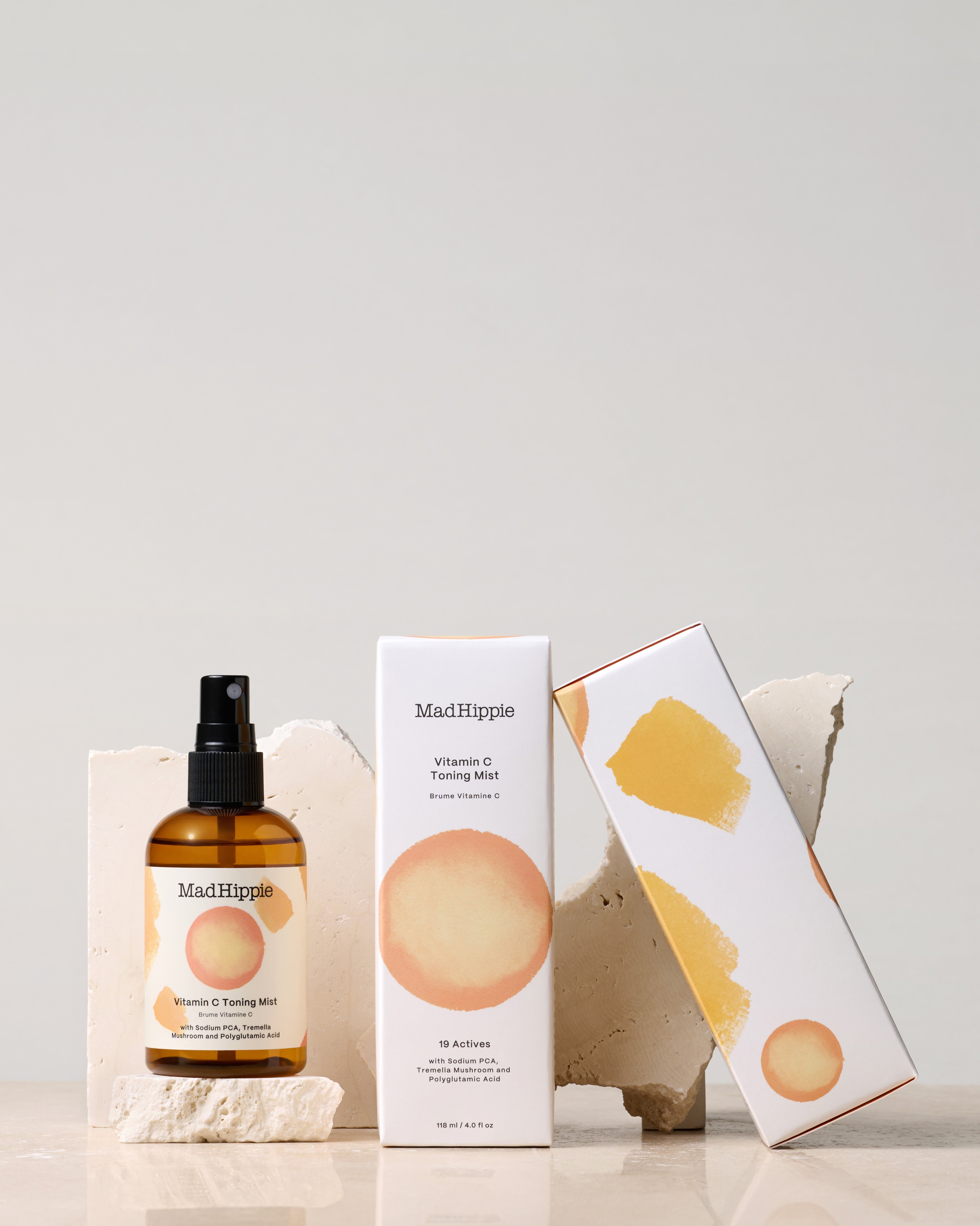 Vitamin C Toning Mist + two boxes in front of stone slabs, with grey background