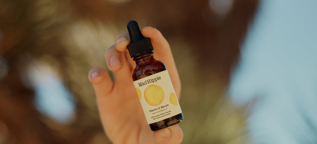 Hand holding Mad Hippie Vitamin C Serum under a Joshua tree
